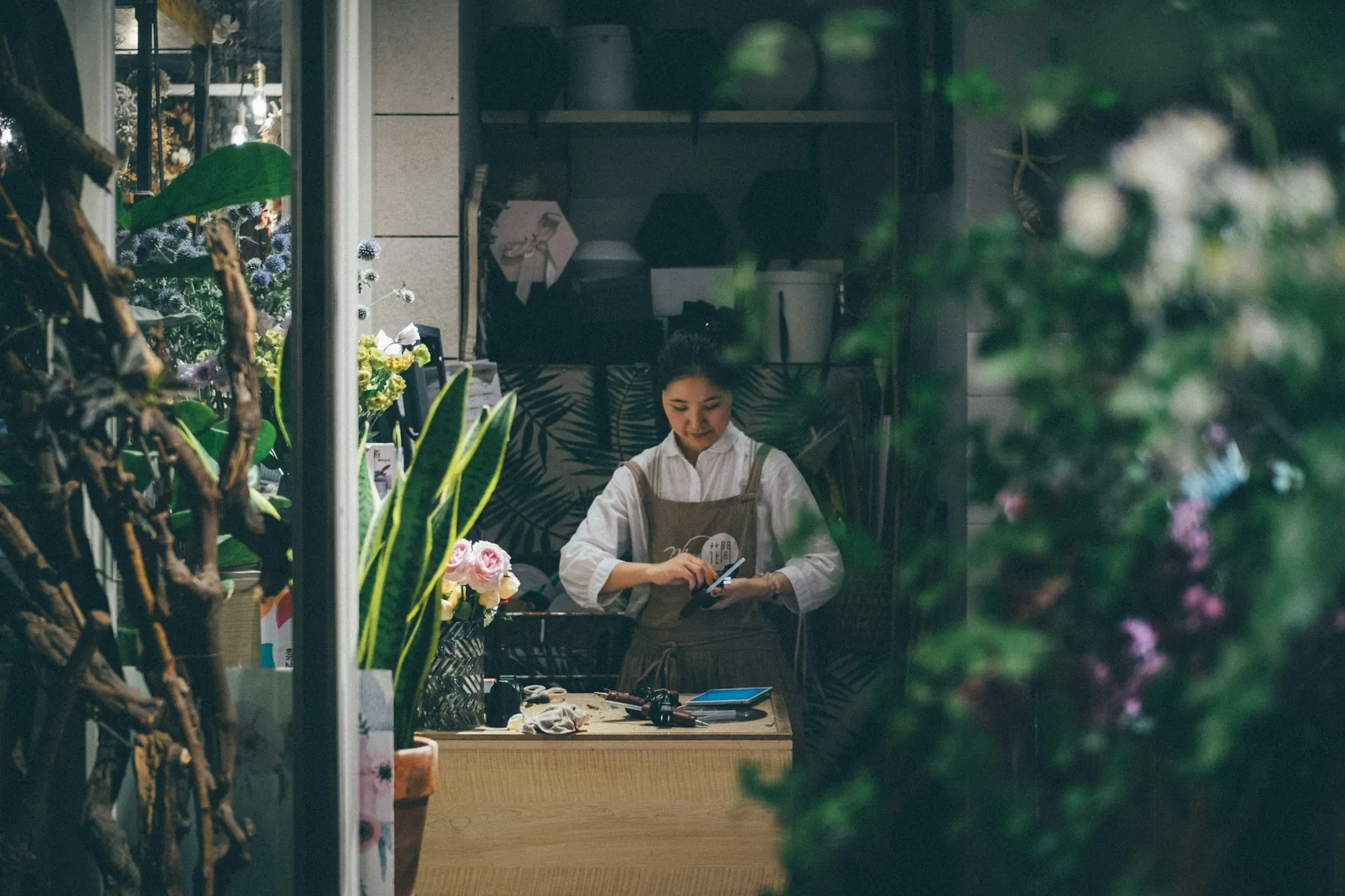 A florist arranging stock inside a plant-filled shop