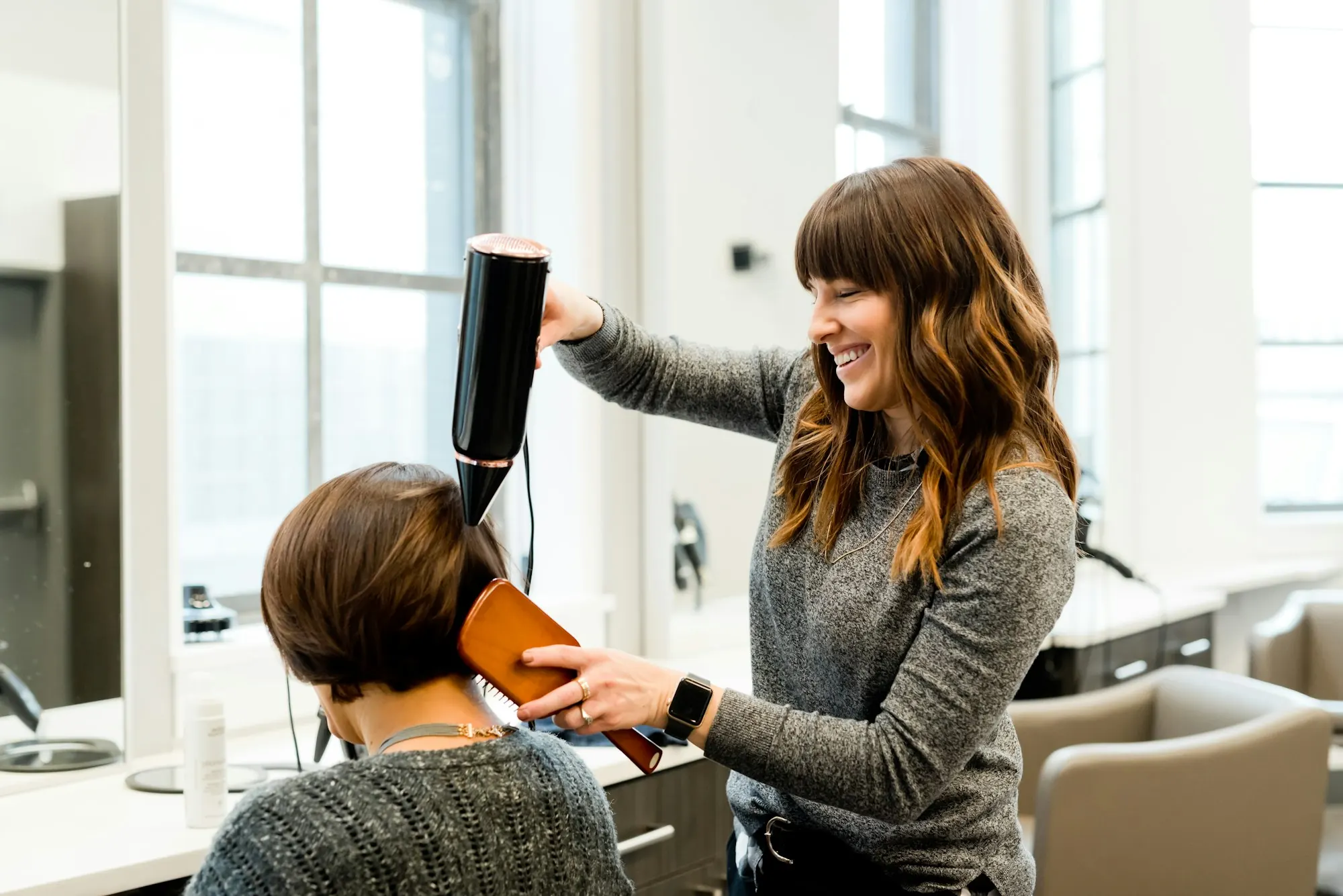 A stylist finishing a blow-dry in a salon chair
